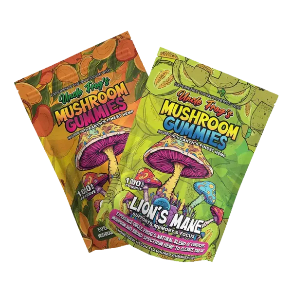 The image shows two angled, three-dimensional packets of "Uncle Frog's MUSHROOM GUMMIES," each with vibrant, colorful artwork featuring a variety of stylized mushrooms on a green background. One package highlights "LION'S MANE" for supporting "memory & focus," while both state the product is "infused with Earth's finest hemp" and "Experience the multiverse with Uncle Frog's natural blend of mushrooms and broad spectrum hemp to elevate your day." The packages boast a playful and psychedelic design aesthetic, with the mushrooms rendered in vivid colors against a patterned background.